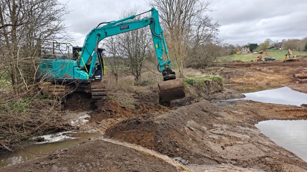 Image of excavators at work landscaping in the brook on a bright but cloudy day